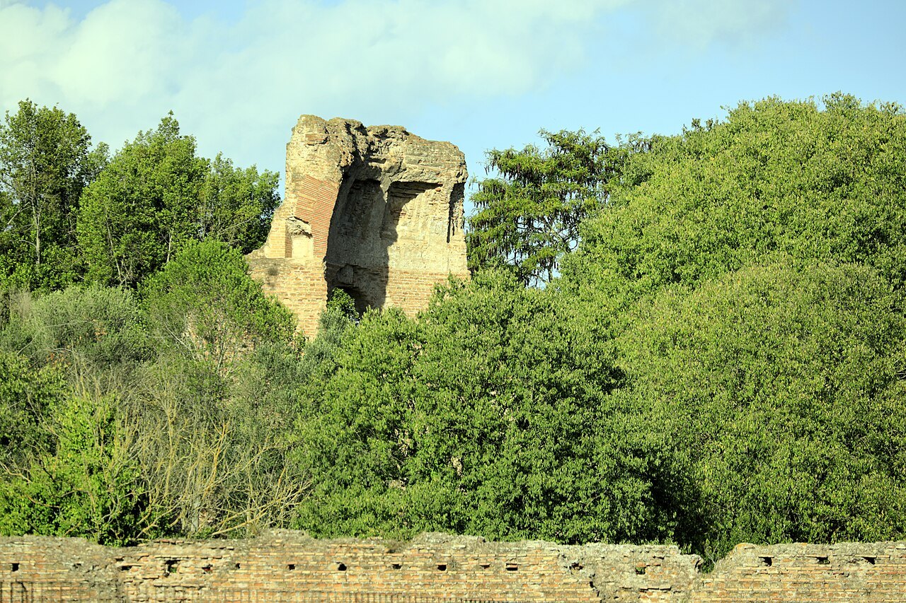 A broken brick ruin of the villa of Maxentius rising above trees beside the Appian Way