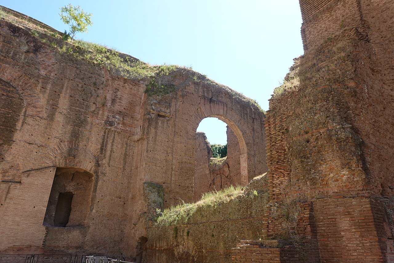 High brick walls of the Baths of Caracalla, an arched opening framing the sky