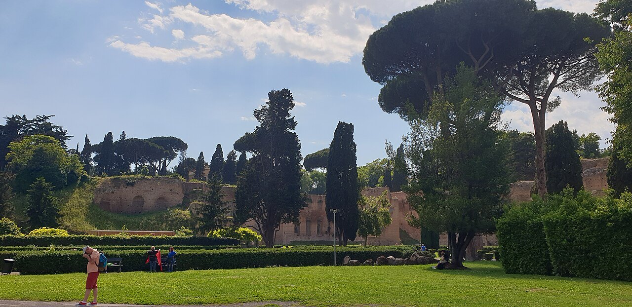 Lawns and umbrella pines in the gardens around the Baths of Caracalla, the ruins low behind the trees