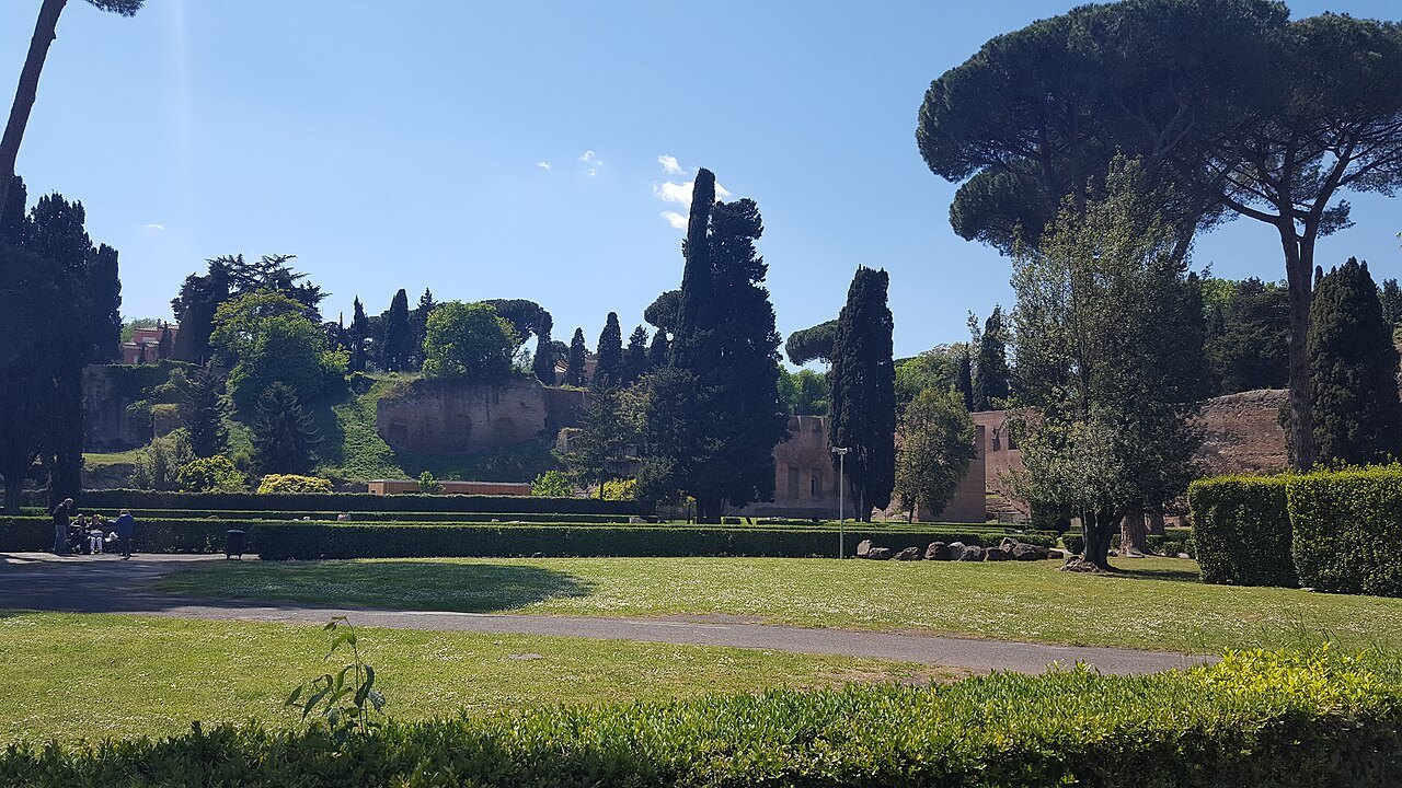 The gardens of the Baths of Caracalla: a lawn, cypresses and umbrella pines under a clear sky