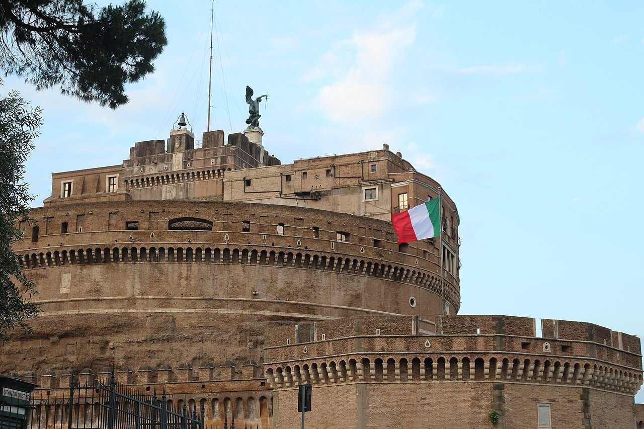 The round drum of Castel Sant'Angelo from the side, an Italian flag on its ramparts
