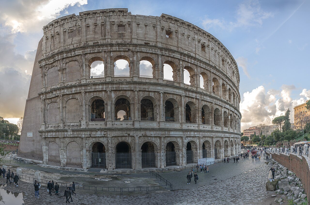 The Colosseum's outer wall seen at a sweeping angle across the cobbled square