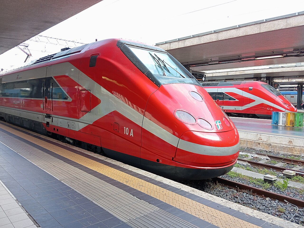 Two red high-speed trains side by side at the platforms of Roma Termini