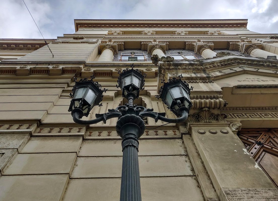 A triple street lamp against the carved stone façade of a building in the old Ghetto