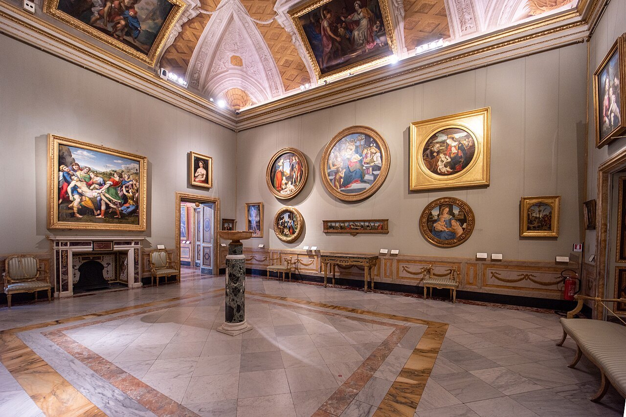 A room of the Borghese Gallery hung with paintings, round frames and marble floors