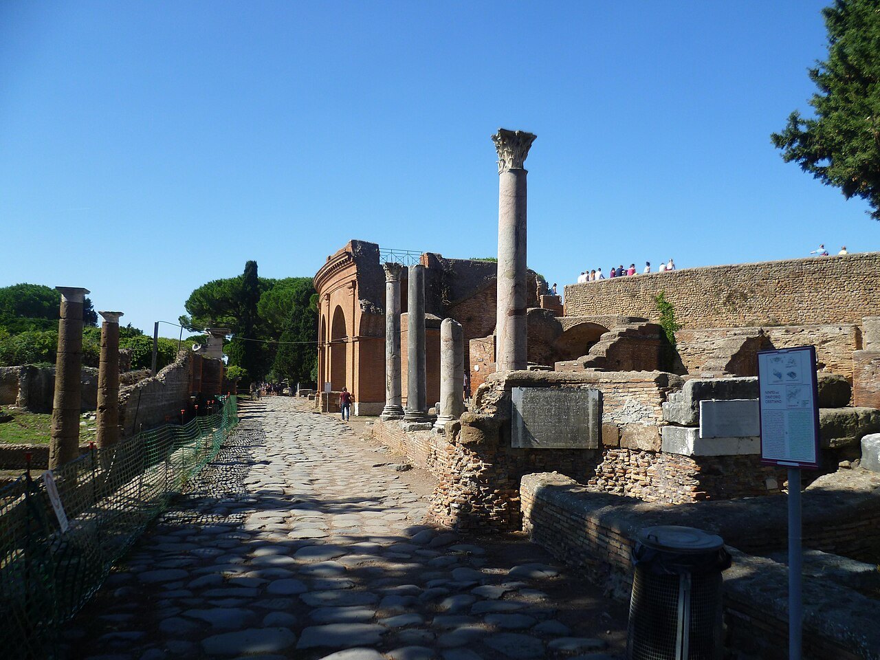 The paved Decumanus Maximus of Ostia Antica, lined with brick ruins and a single column