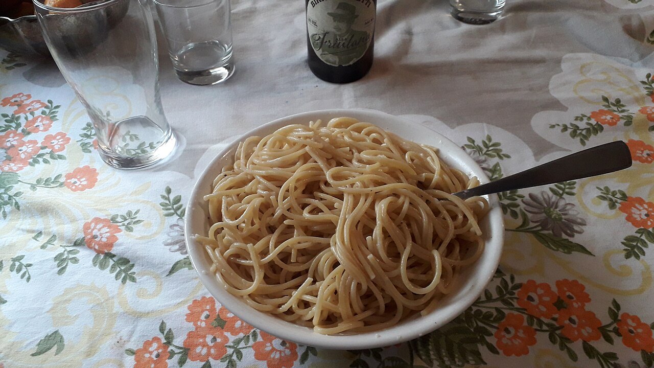 A bowl of spaghetti cacio e pepe on a flowered tablecloth