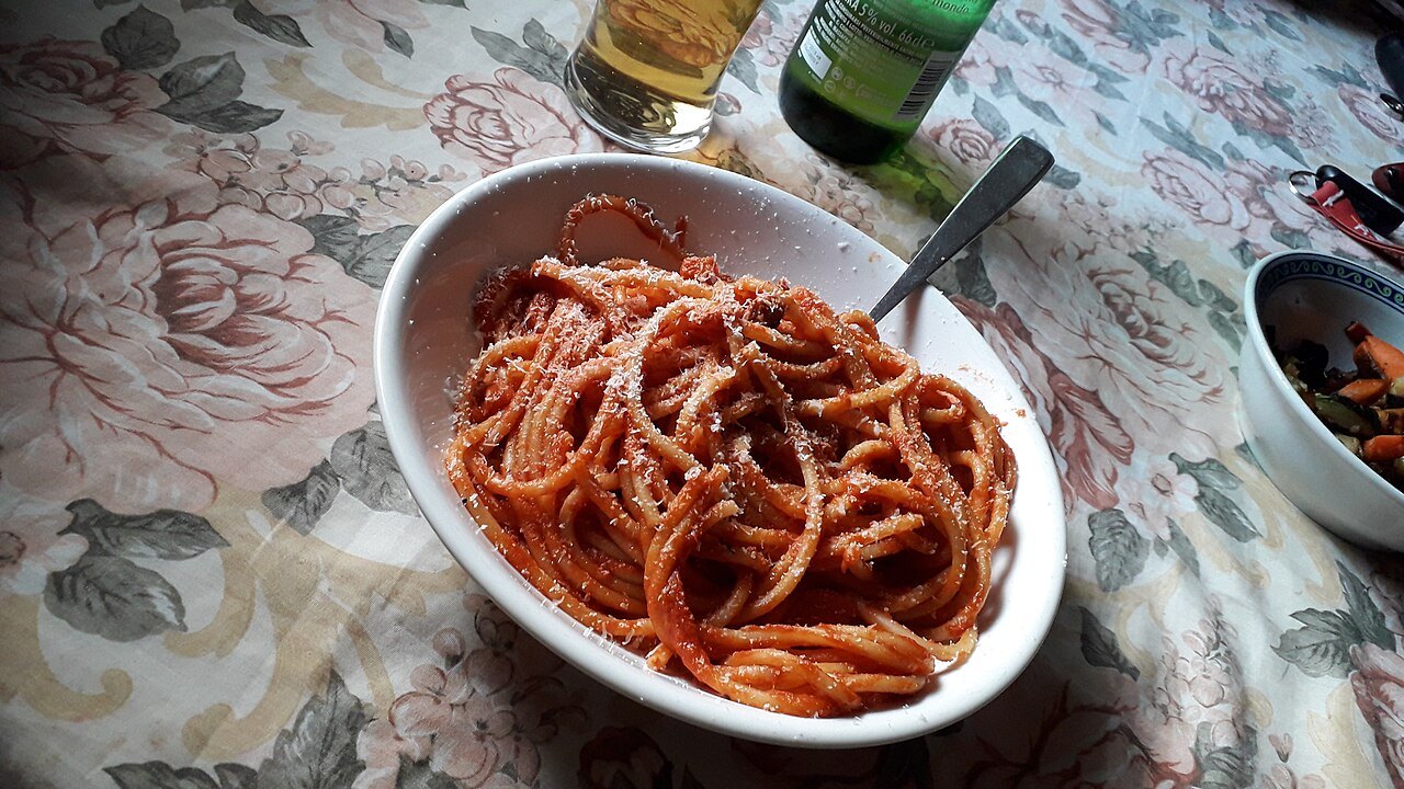 A bowl of bucatini all'amatriciana on a flowered tablecloth