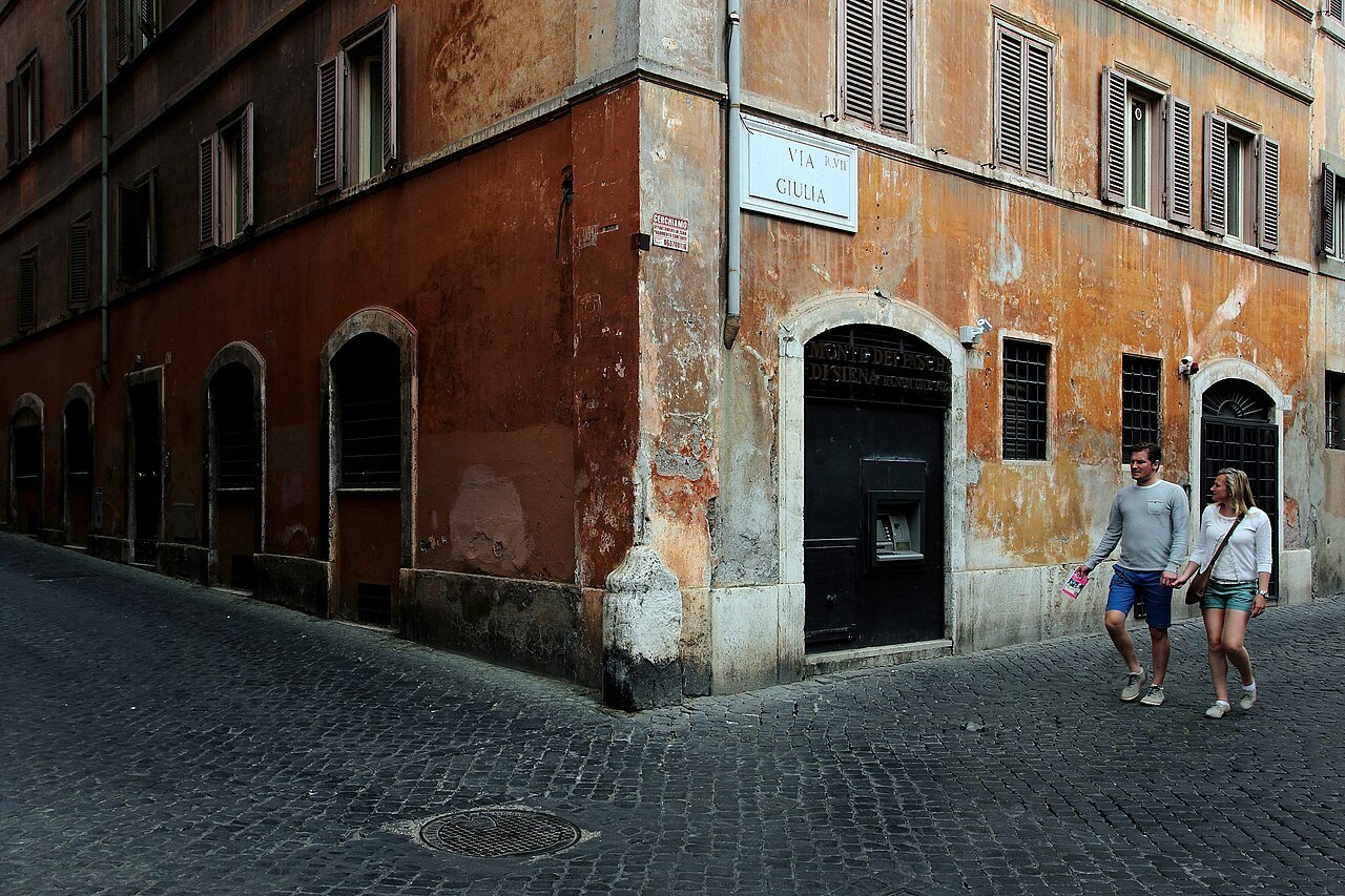 A corner of Via Giulia, weathered red and ocher walls and a street name carved in marble
