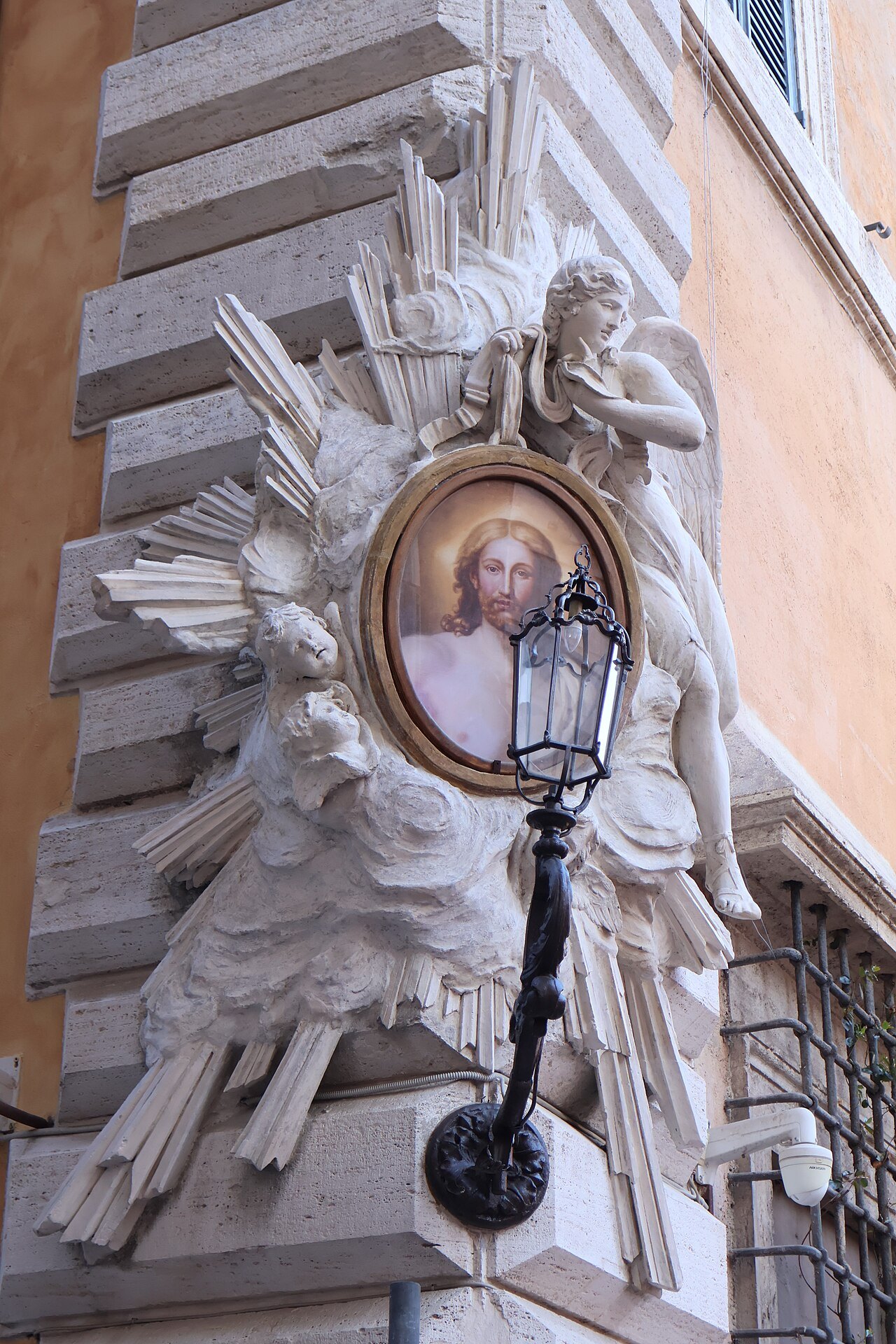 A carved stucco shrine to Christ on a street corner in Via dei Coronari