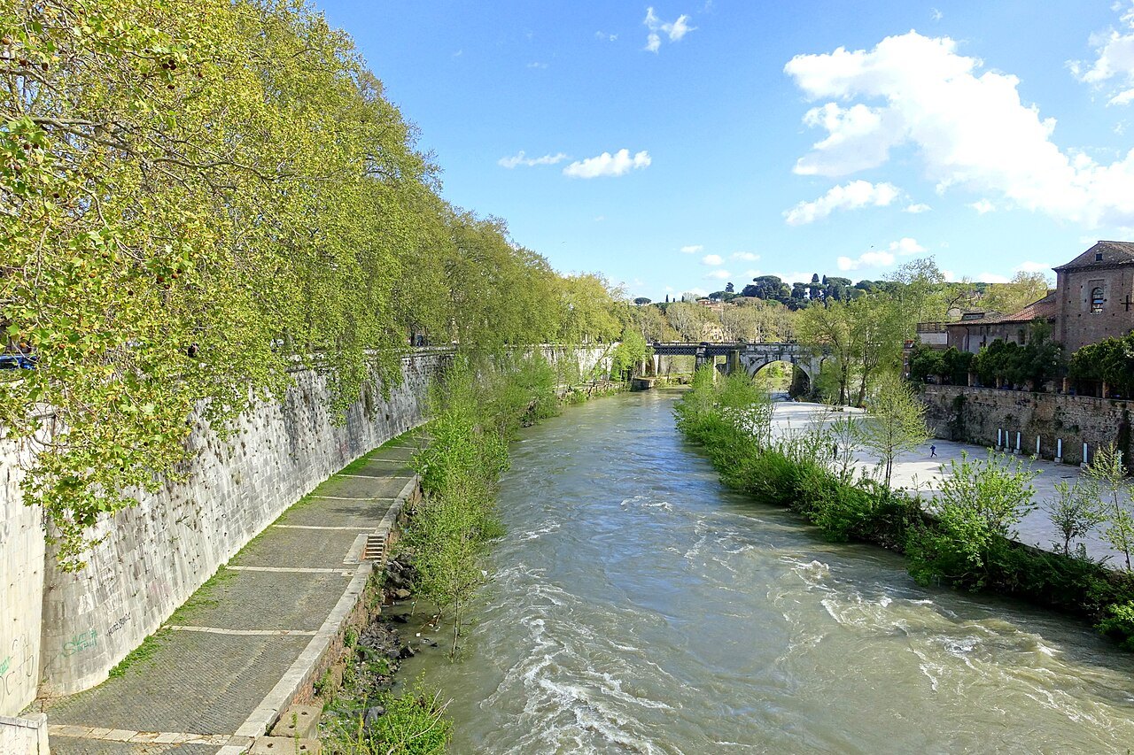 The river wall along the Tiber below the island, green banks and fast water