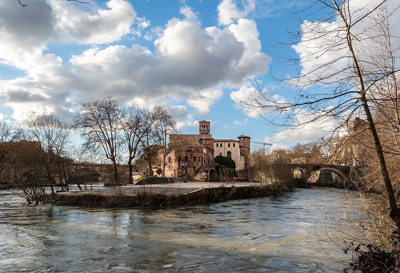 The Tiber Island in winter light, bare trees on the bank and a bridge beyond