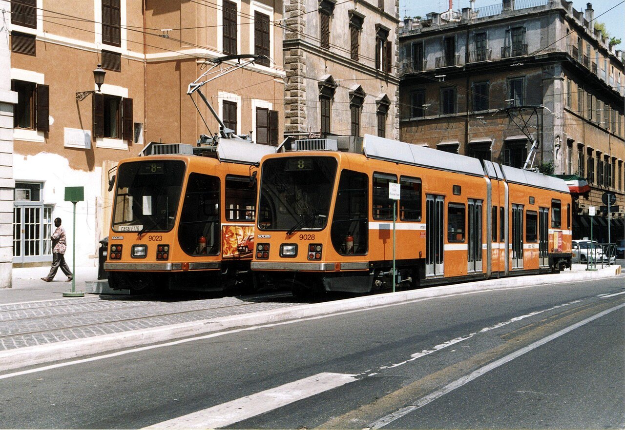 Two orange trams passing in a street of old apartment buildings