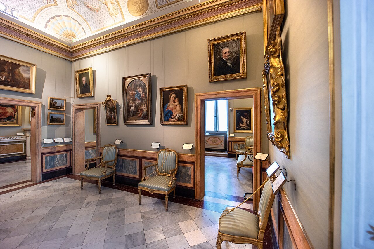 A room of the Borghese Gallery hung with paintings in gilt frames above a marble floor