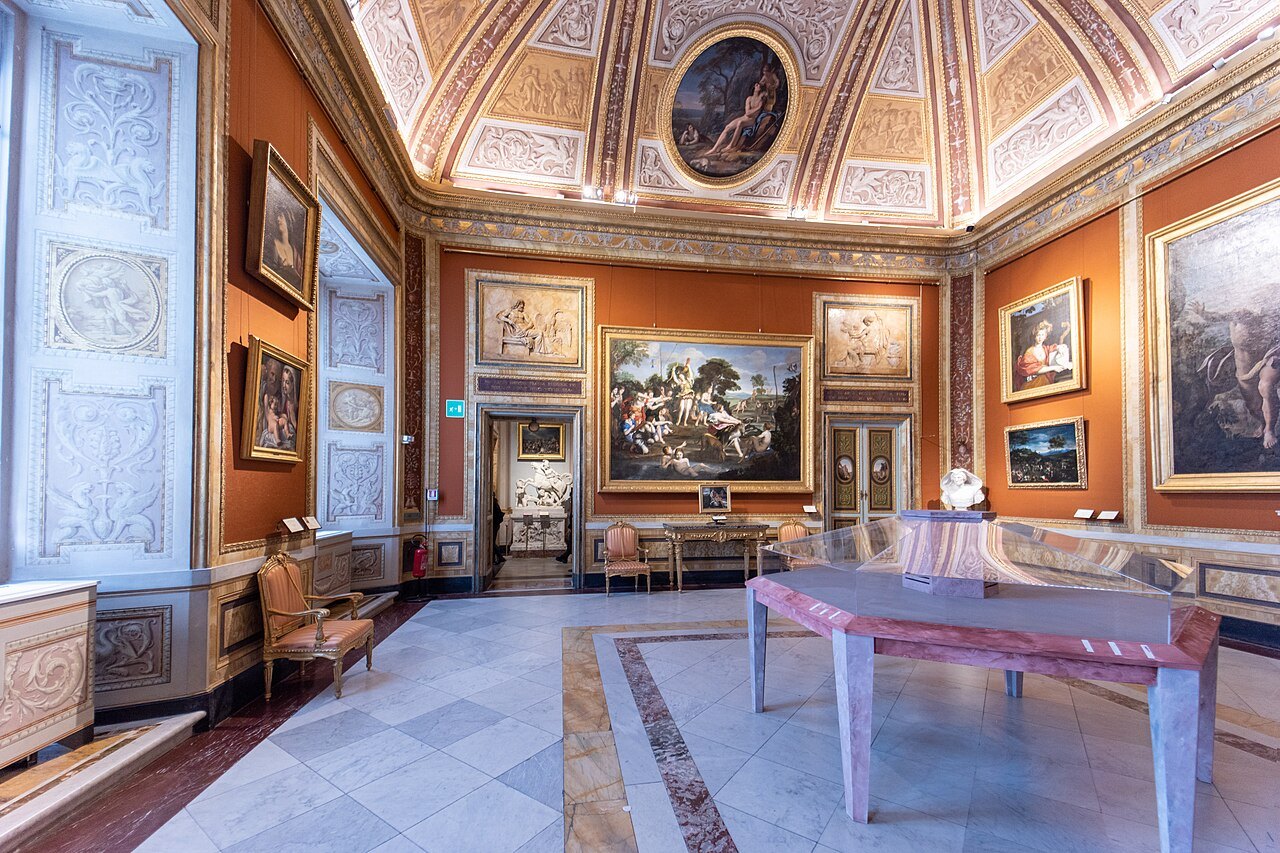 A room of the Borghese Gallery with painted ceiling and walls, a marble table in the middle