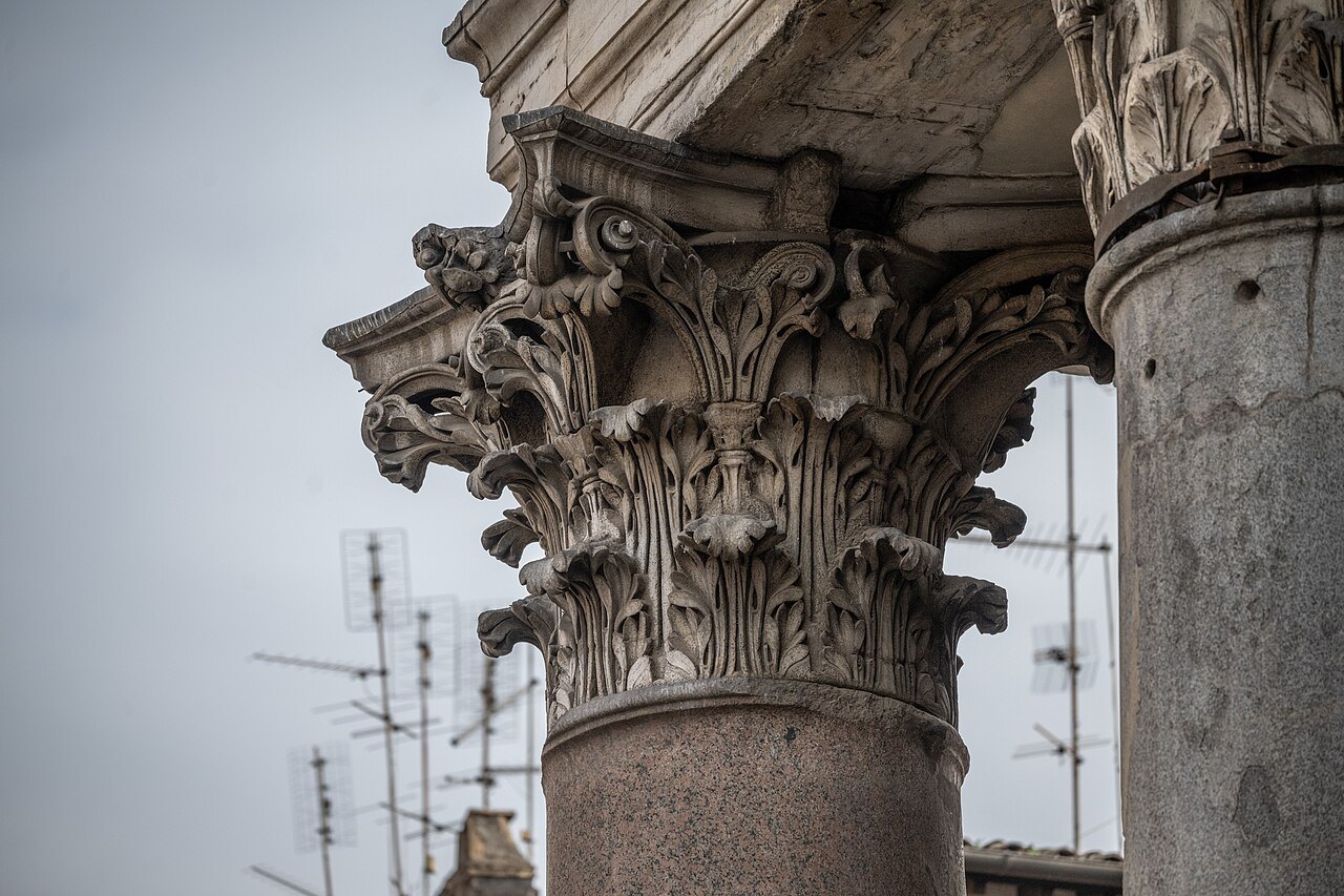 A Corinthian capital of the Pantheon's portico against a gray sky
