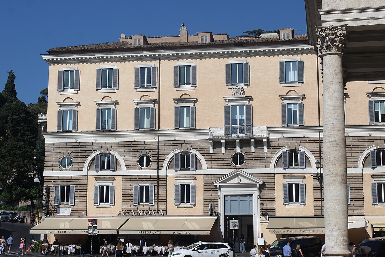 A palace facing Piazza del Popolo, seen past a column of Santa Maria dei Miracoli