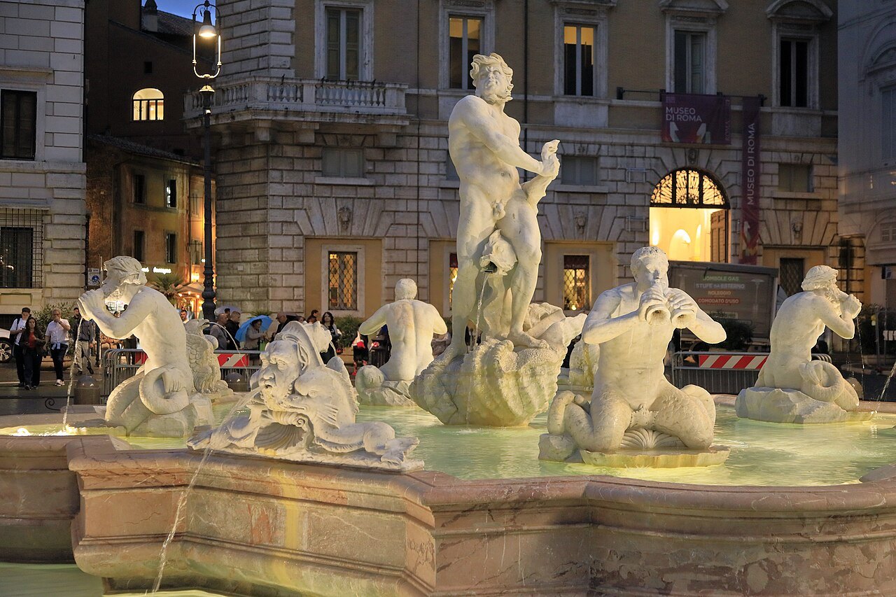 The Moor and the tritons of the fountain at the south end of Piazza Navona, lit at evening