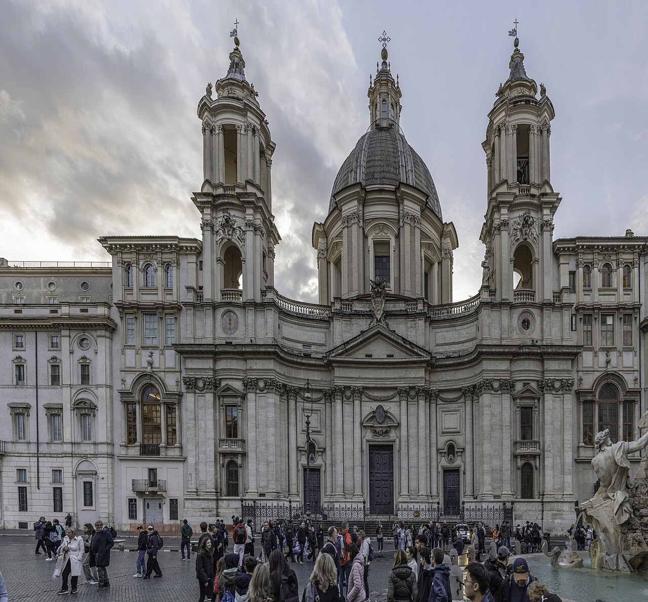 Borromini's Sant'Agnese in Agone on Piazza Navona under a cloudy sky, people crossing the square