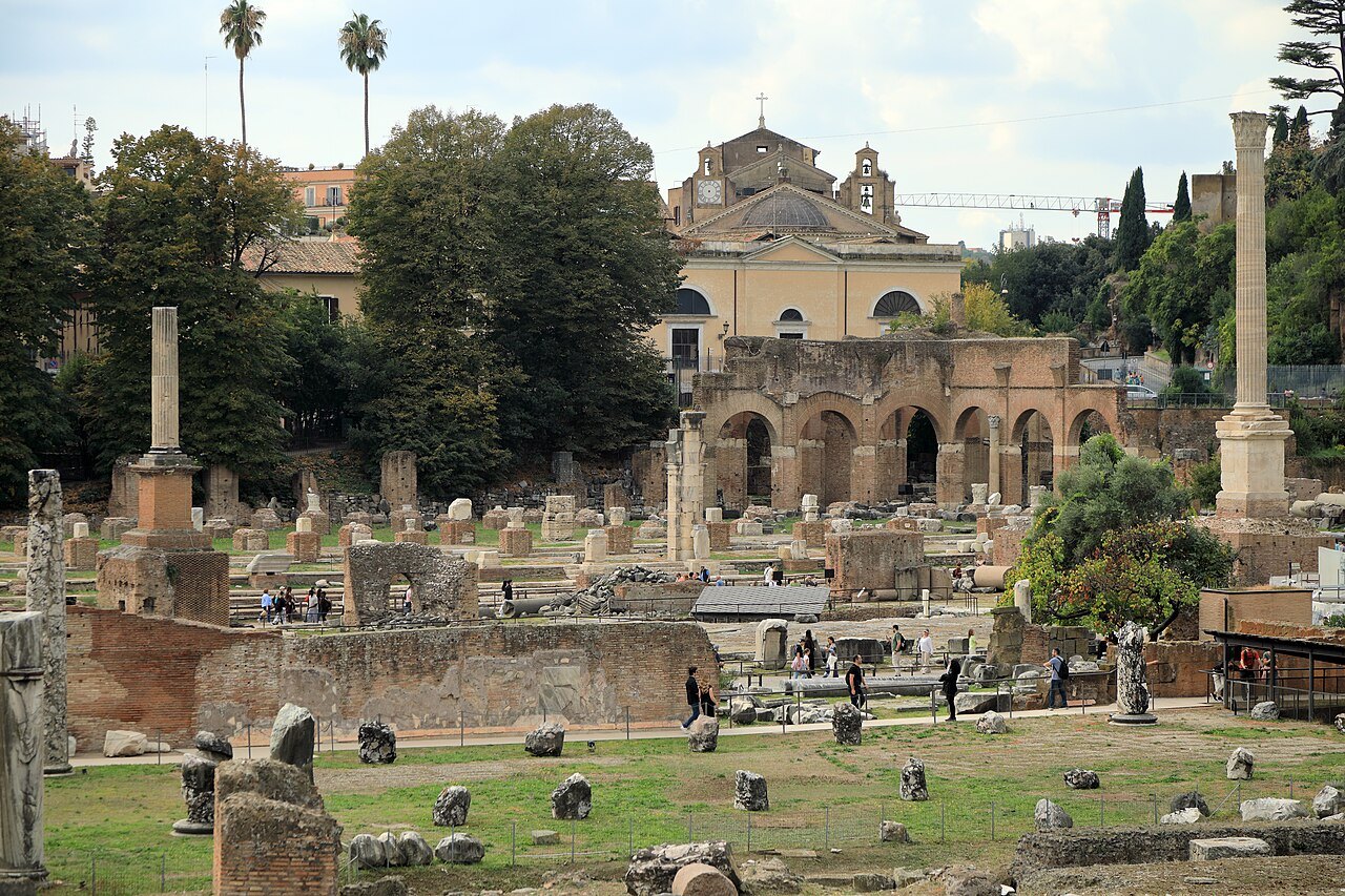 The Basilica Julia's paving and column bases, a church behind the trees
