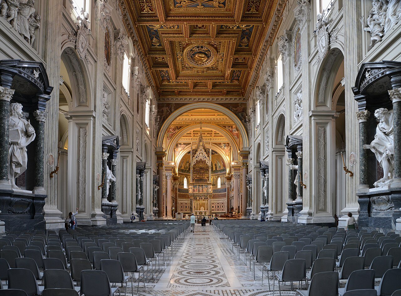 The nave of St. John Lateran lined with colossal apostles, chairs set out for a service