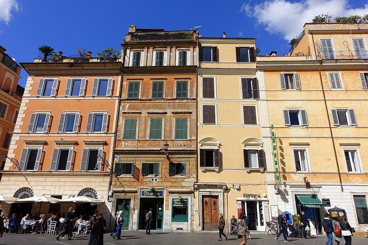 The colored house fronts of the square of Santa Maria in Trastevere, café tables below