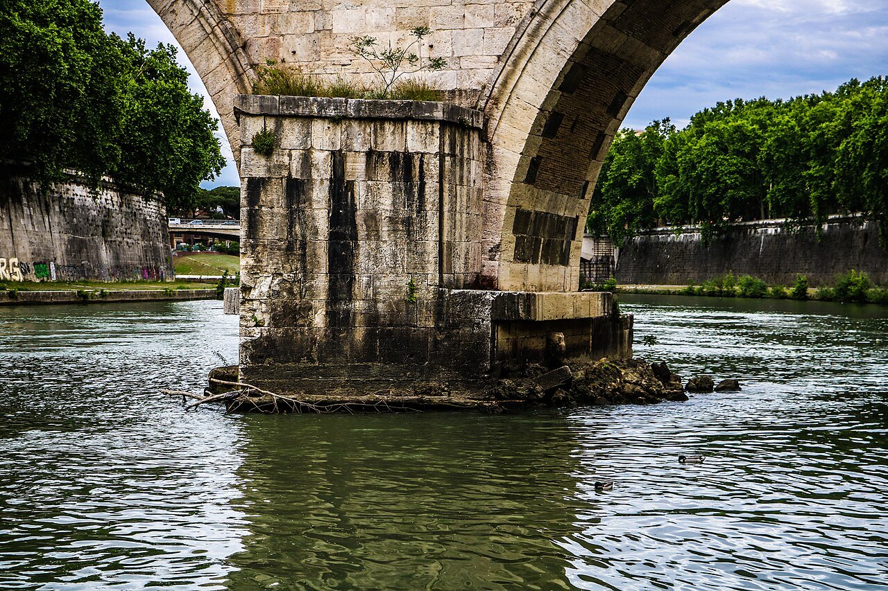 A pier of the Ponte Sisto standing in the green water of the Tiber