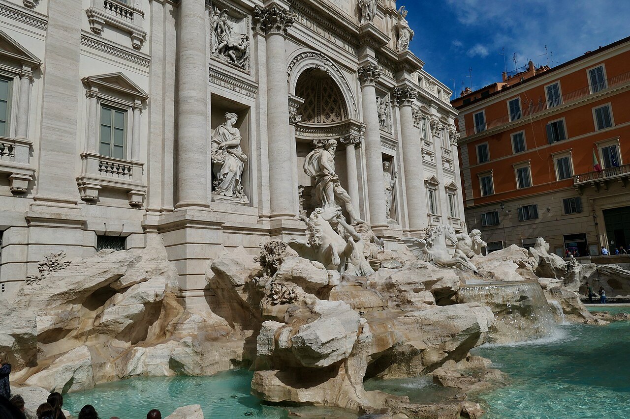 A close view of the Trevi Fountain: rocks, sculpted figures and the turquoise basin