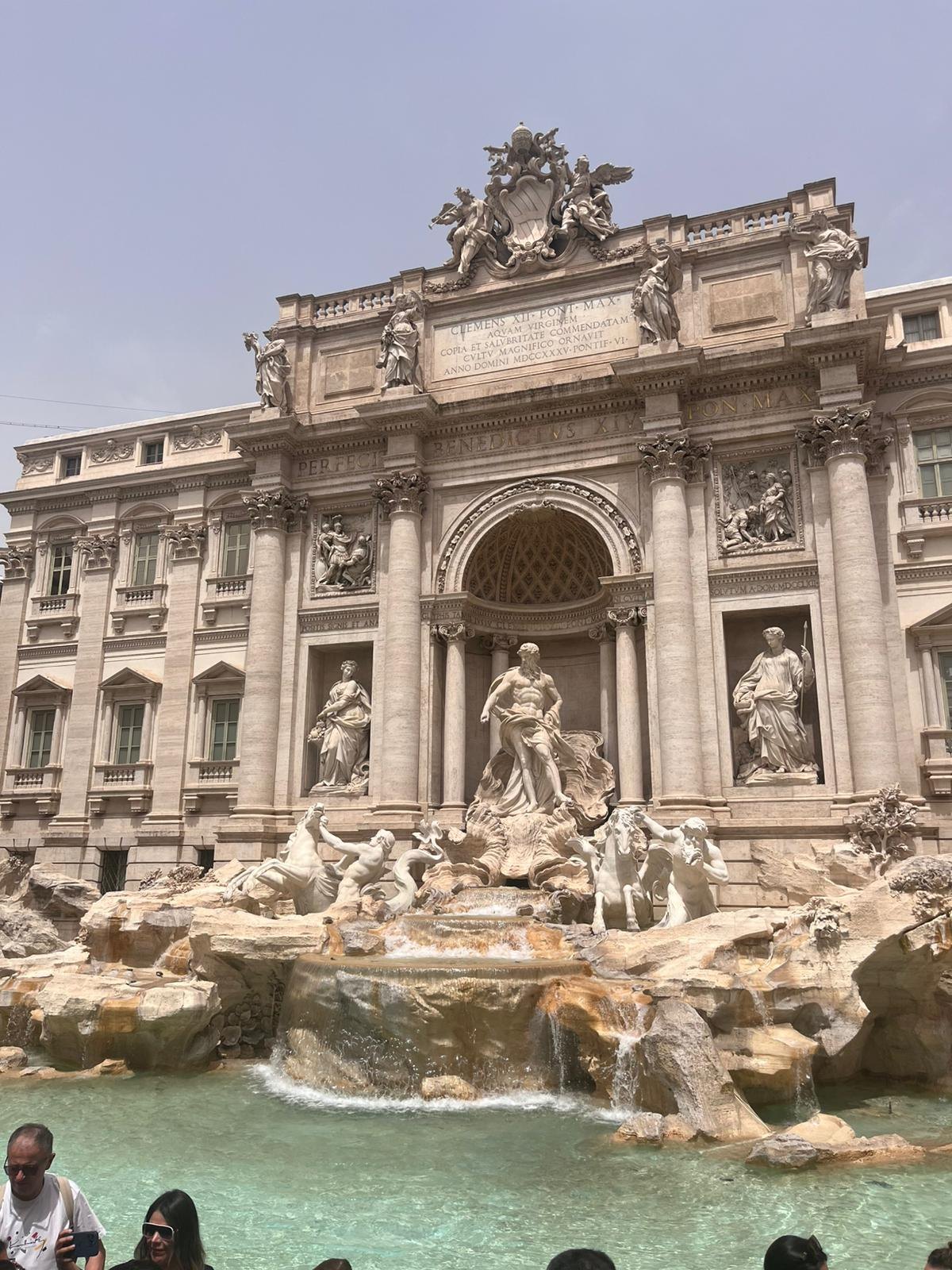 The Trevi Fountain seen from one side of its small square, visitors along the basin
